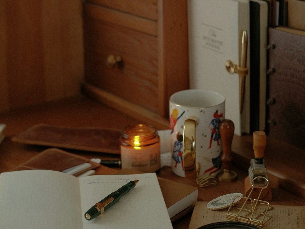 An open notebook and pen on a warm wooden desk.